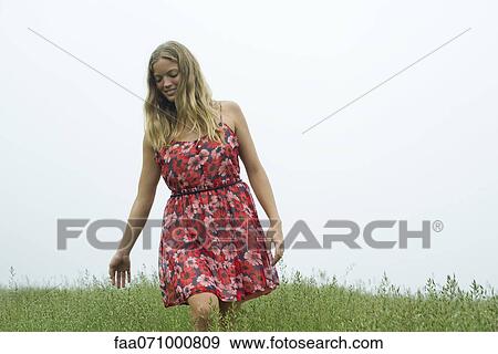 Stock Photo - Young woman walking in tall grass. Fotosearch