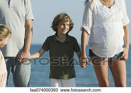 Boy at the beach with his family, holding his parents' hands View Large Photo Image Stock Image - Boy at the beach with his family, holding his parents' hands. Fotosearch