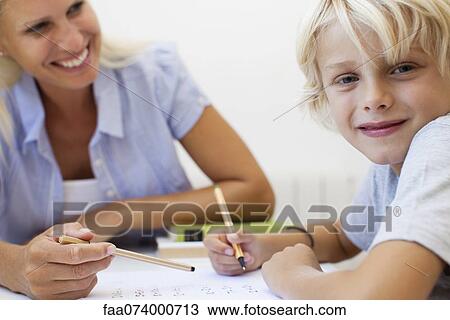 Stock Image - Boy doing homework, smiling at camera. Fotosearch
