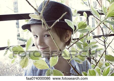 Boy looking through foliage at camera, portrait View Large Photo Image Stock Photograph - Boy looking through foliage at camera, portrait. Fotosearch