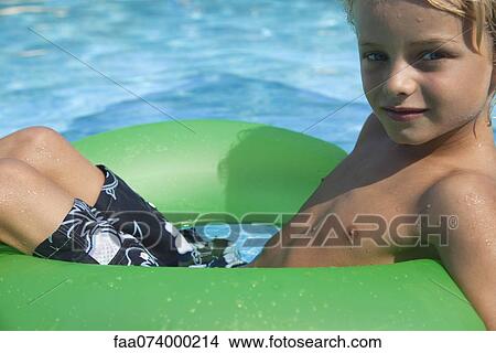 Boy relaxing on float in pool, portrait View Large Photo Image Picture - Boy relaxing on float in pool, portrait. Fotosearch