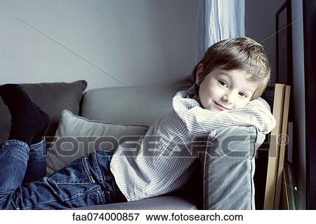 Stock Photo - Boy relaxing on sofa, portrait. Fotosearch