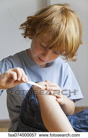 Boy removing adhesive bandage from knee View Large Photo Image Stock Photo - Boy removing adhesive bandage from knee. Fotosearch
