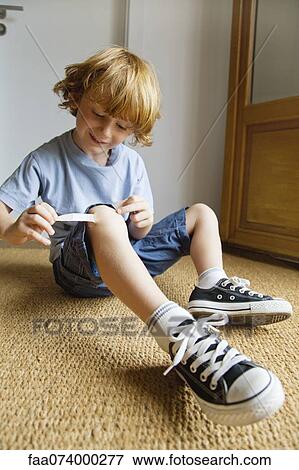 Boy removing adhesive bandage from knee View Large Photo Image Stock Photo - Boy removing adhesive bandage from knee. Fotosearch