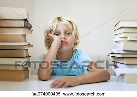 Boy sitting between two stacks of books with bored expression View Large Photo Image Stock Photography - Boy sitting between two stacks of books with bored expression. Fotosearch