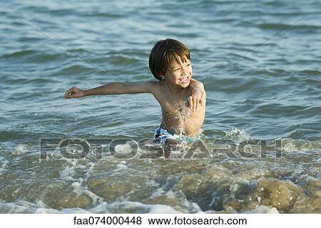 Stock Photo - Boy splashing in water at the beach. Fotosearch