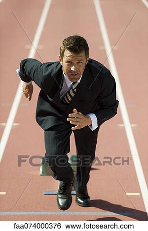 Businessman at starting line on running track View Large Photo Image Stock Photograph - Businessman at starting line on running track. Fotosearch