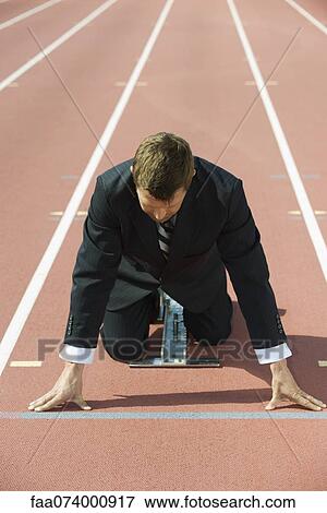 Businessman crouching at starting line on running track View Large Photo Image Stock Photo - Businessman crouching at starting line on running track. Fotosearch