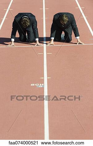 Stock Image - Businessmen crouched in starting position on running track. Fotosearch