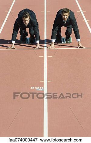 Businessmen crouched in starting position on running track View Large Photo Image Stock Photo - Businessmen crouched in starting position on running track. Fotosearch