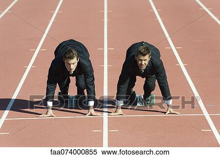 Stock Photography - Businessmen crouched in starting position on running track. Fotosearch
