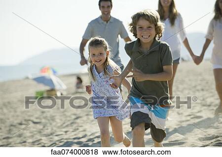 Children running at the beach, family in background View Large Photo Image Stock Photo - Children running at the beach, family in background. Fotosearch
