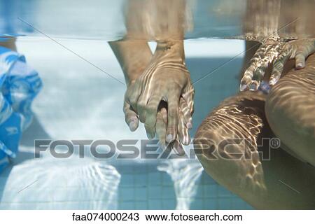 Stock Image - Couple holding hands underwater, cropped. Fotosearch