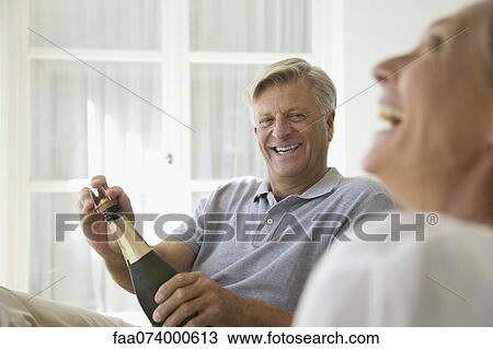 Couple relaxing together, man opening bottle of champagne View Large Photo Image Stock Image - Couple relaxing together, man opening bottle of champagne. Fotosearch