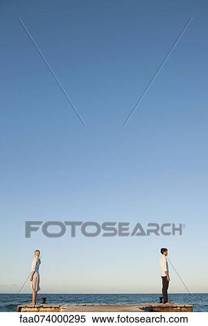 Couple standing back to back on pier, side view View Large Photo Image Stock Photography - Couple standing back to back on pier, side view. Fotosearch