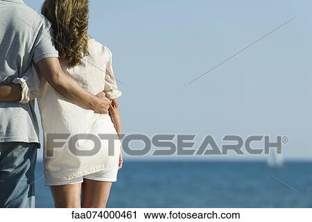 Stock Image - Couple together at the beach, rear view. Fotosearch