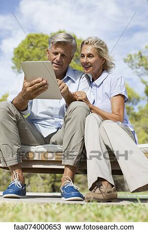 Stock Image - Couple using digital tablet outdoors. Fotosearch