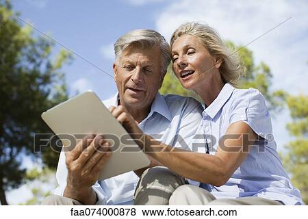Couple using digital tablet outdoors View Large Photo Image Stock Photo - Couple using digital tablet outdoors. Fotosearch
