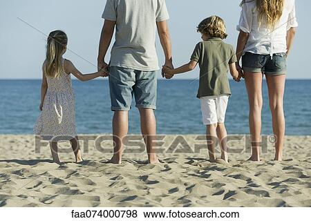 Family holding hands at the beach, rear view View Large Photo Image Stock Photo - Family holding hands at the beach, rear view. Fotosearch