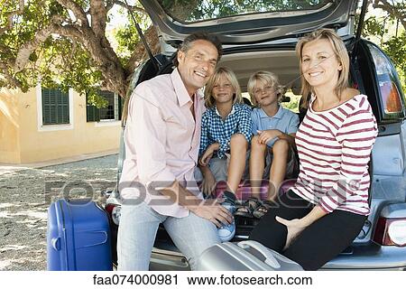 Stock Image - Family sitting together in back of car with open hatchback. Fotosearch