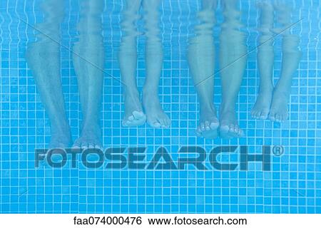 Stock Photograph - Family soaking feet in pool, underwater view. Fotosearch