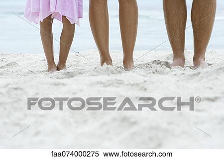 Stock Photography - Family staning on beach, low section. Fotosearch