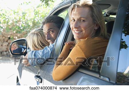Family together in car, leaning out windows and smiling over shoulders at camera View Large Photo Image Picture - Family together in car, leaning out windows and smiling over shoulders at camera. Fotosearch