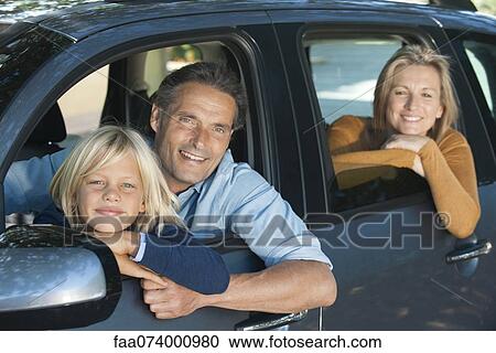 Stock Image - Family together in car, leaning out windows and smiling at camera. Fotosearch