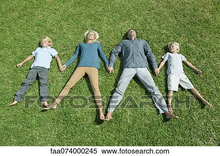 Family with two children lying side by side hand in hand on lawn, high angle view View Large Photo Image Stock Photography - Family with two children lying side by side hand in hand on lawn, high angle view. Fotosearch