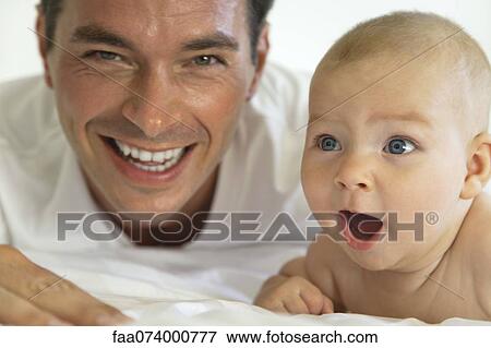 Stock Photo - Father and baby laughing together, portrait. Fotosearch