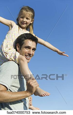 Stock Image - Father carrying daughter on his shoulders. Fotosearch