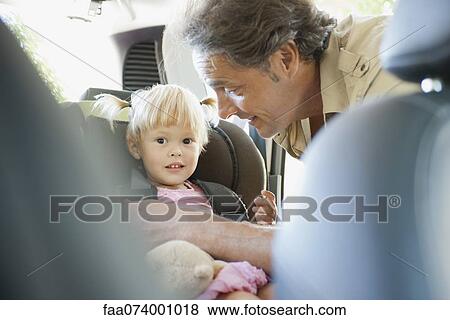 Stock Photo - Father fastening little girl into car seat. Fotosearch