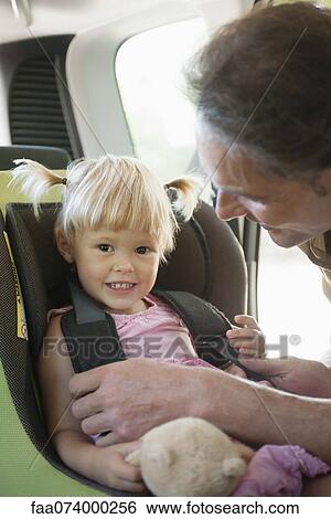 Father fastening little girl into car seat View Large Photo Image Stock Photograph - Father fastening little girl into car seat. Fotosearch