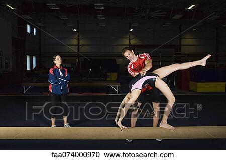 Female gymnast practicing on balance beam with coach View Large Photo Image Stock Image - Female gymnast practicing on balance beam with coach. Fotosearch