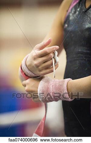 Female gymnast wrapping wrists in preparation, cropped View Large Photo Image Stock Photograph - Female gymnast wrapping wrists in preparation, cropped. Fotosearch