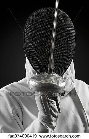 Stock Photo - Fencer holding up foil, portrait. Fotosearch