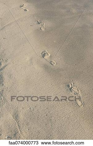 Stock Image - Footprints in sand, high angle view. Fotosearch