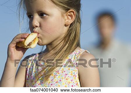 Stock Image - Girl eating sandwich outdoors. Fotosearch