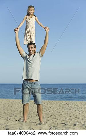 Girl standing on father's shoulders at the beach View Large Photo Image Stock Image - Girl standing on father's shoulders at the beach. Fotosearch