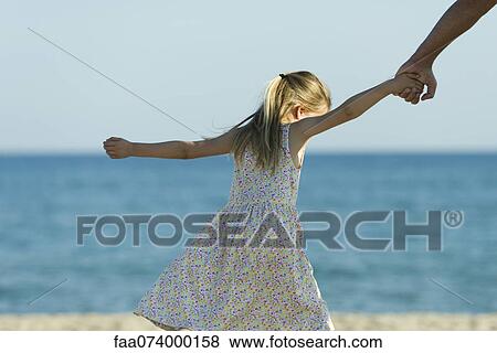 Girl walking at the beach, holding parent's hand, cropped View Large Photo Image Stock Photo - Girl walking at the beach, holding parent's hand, cropped. Fotosearch