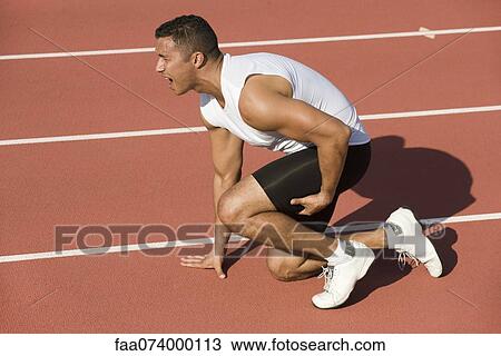 Stock Image - Injured runner kneeling on running track. Fotosearch