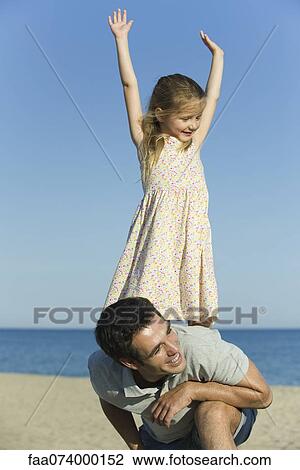 Stock Image - Little girl balancing on her father's back. Fotosearch
