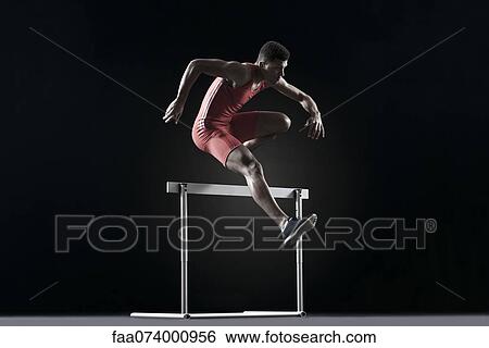 Stock Photograph - Male athlete cearling hurdle. Fotosearch