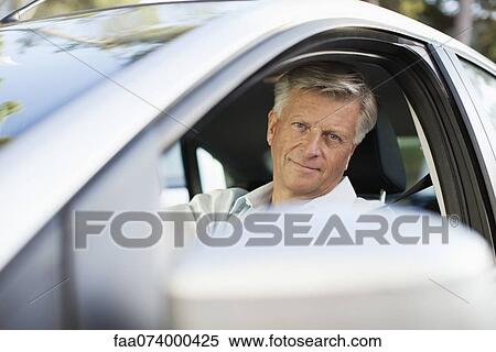 Man driving car, looking out window at camera View Large Photo Image Stock Photography - Man driving car, looking out window at camera. Fotosearch