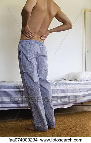 Man experiencing lower back pain, croppeds View Large Photo Image Picture - Man experiencing lower back pain, croppeds. Fotosearch