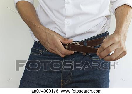 Stock Photograph - Man fastening belt, mid section. Fotosearch
