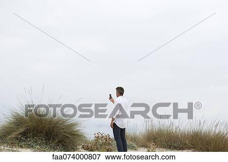 Man holding cell phone outdoors View Large Photo Image Stock Photo - Man holding cell phone outdoors. Fotosearch