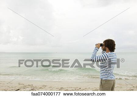 Stock Photo - Man looking at view through binoculars. Fotosearch