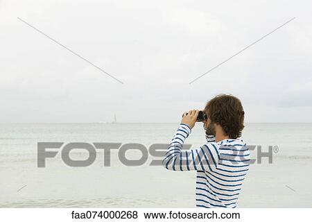 Stock Photo - Man looking at view through binoculars. Fotosearch