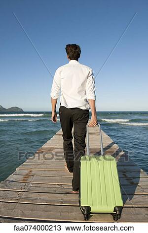 Man pulling luggage and walking on pier, rear view View Large Photo Image Stock Image - Man pulling luggage and walking on pier, rear view. Fotosearch